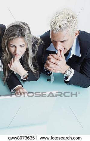 Stock Image - Businessman and a businesswoman looking at a laptop and thinking. Fotosearch