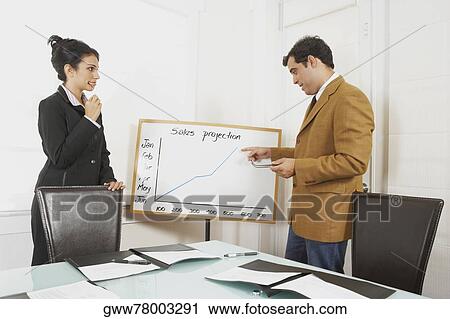 Businessman giving a graph presentation to a businesswoman View Large Photo Image Stock Image - Businessman giving a graph presentation to a businesswoman. Fotosearch