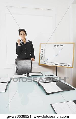 Stock Image - Businesswoman standing in a conference room. Fotosearch
