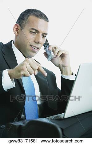 Close-up of a businessman talking on a mobile phone and using a laptop View Large Photo Image Stock Image - Close-up of a businessman talking on a mobile phone and using a laptop. Fotosearch