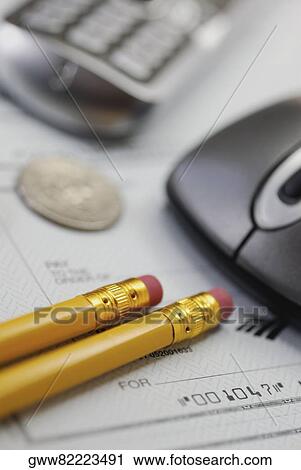 Stock Image - Close-up of a computer mouse with pencils and a mobile phone on a check. Fotosearch