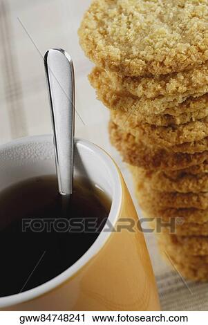 Stock Image - Close-up of a cup of coffee with cookies. Fotosearch