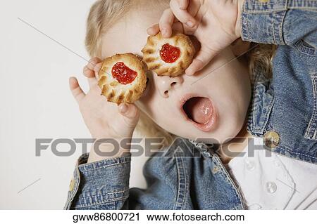 Close-up of a girl holding two biscuits on her eyes View Large Photo Image Stock Image - Close-up of a girl holding two biscuits on her eyes. Fotosearch