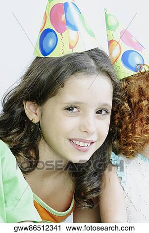 Close-up of a girl wearing a birthday hat and smiling View Large Photo Image Stock Image - Close-up of a girl wearing a birthday hat and smiling. Fotosearch