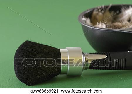 Stock Image - Close-up of a make-up brush with a bowl of feathers beside it. Fotosearch