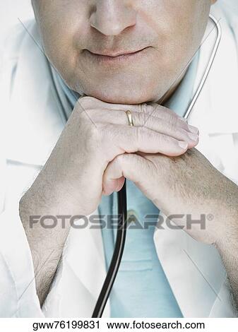 Close-up of a male doctor resting his chin on his hands View Large Photo Image Stock Image - Close-up of a male doctor resting his chin on his hands. Fotosearch