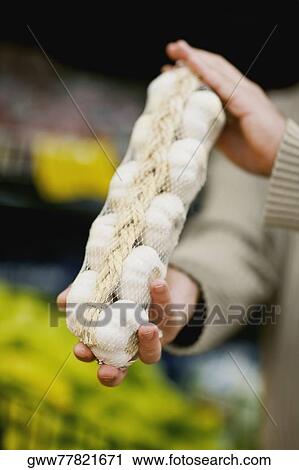 Close-up of a man's hands holding a packet of garlic View Large Photo Image Stock Image - Close-up of a man's hands holding a packet of garlic. Fotosearch