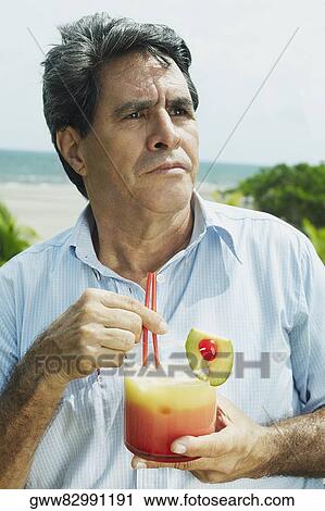 Close-up of a mature man holding a glass of juice View Large Photo Image Stock Image - Close-up of a mature man holding a glass of juice. Fotosearch