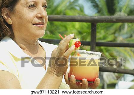 Close-up of a mature woman holding a glass of juice View Large Photo Image Stock Image - Close-up of a mature woman holding a glass of juice. Fotosearch