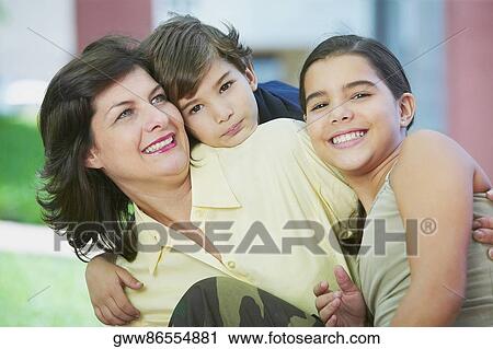 Close-up of a mature woman smiling with her children View Large Photo Image Stock Image - Close-up of a mature woman smiling with her children. Fotosearch