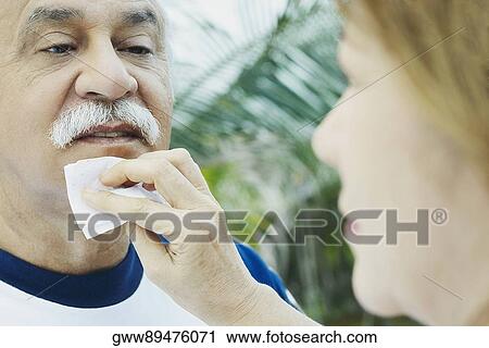 Stock Image - Close-up of a mature woman wiping a senior man's chin. Fotosearch
