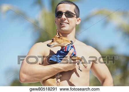 Stock Image - Close-up of a mid adult man holding a puppy. Fotosearch