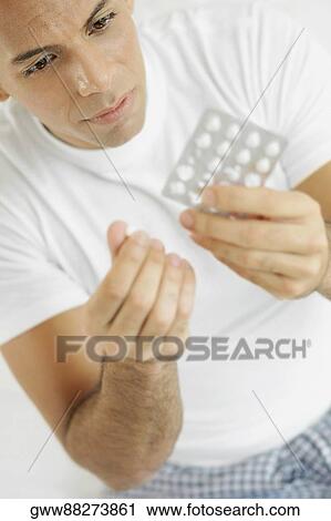 Close-up of a mid adult man holding a pill and a blister pack View Large Photo Image Stock Image - Close-up of a mid adult man holding a pill and a blister pack. Fotosearch