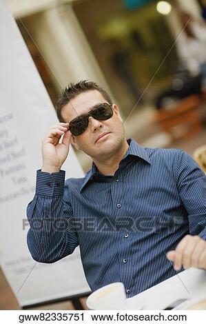 Close-up of a mid adult man holding his sunglasses View Large Photo Image Stock Image - Close-up of a mid adult man holding his sunglasses. Fotosearch