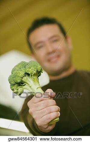 Close-up of a mid adult man holding broccoli View Large Photo Image Stock Image - Close-up of a mid adult man holding broccoli. Fotosearch