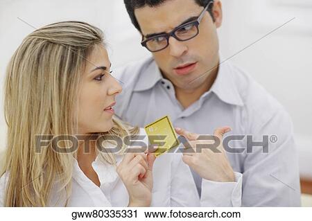 Close-up of a mid adult woman holding a credit card with a mid adult man looking at her View Large Photo Image Stock Image - Close-up of a mid adult woman holding a credit card with a mid adult man looking at her. Fotosearch
