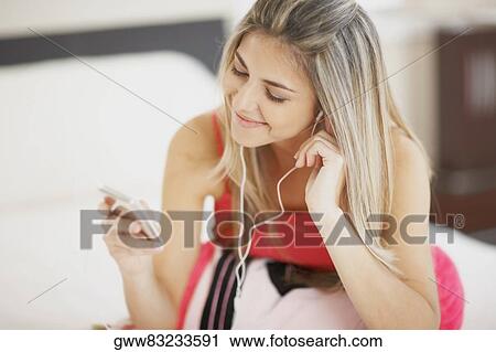 Stock Image - Close-up of a mid adult woman listening to an MP3 player. Fotosearch