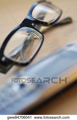 Close-up of a pair of eyeglasses with a mobile phone View Large Photo Image Stock Image - Close-up of a pair of eyeglasses with a mobile phone. Fotosearch