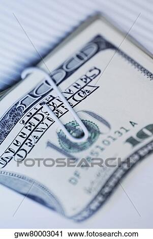 Stock Image - Close-up of a paper clip attached on one hundred dollar bills. Fotosearch