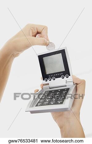 Close-up of a person's hand inserting a coin into a calculator View Large Photo Image Stock Image - Close-up of a person's hand inserting a coin into a calculator. Fotosearch