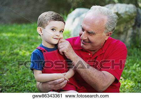 Stock Image - Close-up of a senior man pinching his grandson's cheek. Fotosearch