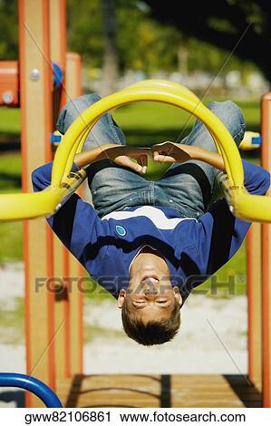 Close-up of a teenage boy hanging upside down on a jungle gym View Large Photo Image Stock Image - Close-up of a teenage boy hanging upside down on a jungle gym. Fotosearch