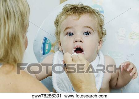 Stock Image - Close-up of a woman feeding her son. Fotosearch