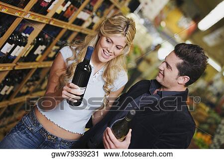 Close-up of a young couple holding wine bottles in a liquor store View Large Photo Image Stock Image - Close-up of a young couple holding wine bottles in a liquor store. Fotosearch