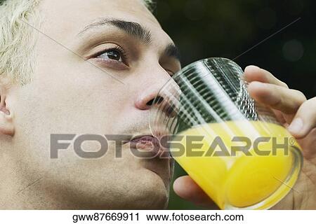 Close-up of a young man drinking a glass of orange juice View Large Photo Image Stock Image - Close-up of a young man drinking a glass of orange juice. Fotosearch
