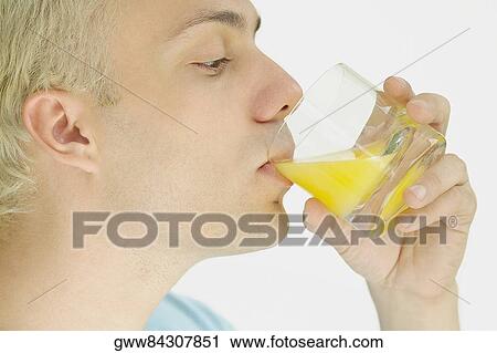 Close-up of a young man drinking orange juice from a glass View Large Photo Image Stock Image - Close-up of a young man drinking orange juice from a glass. Fotosearch