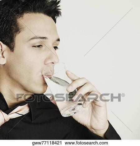 Stock Image - Close-up of a young man drinking water from a glass. Fotosearch
