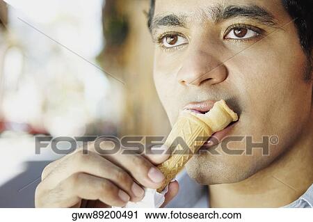 Stock Image - Close-up of a young man eating an ice-cream cone. Fotosearch