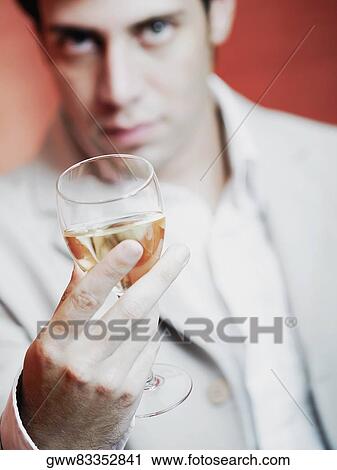 Stock Image - Close-up of a young man holding a glass of wine. Fotosearch