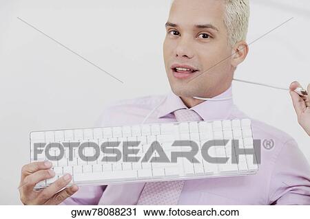 Close-up of a young man holding a keyboard with a wire around his neck View Large Photo Image Stock Image - Close-up of a young man holding a keyboard with a wire around his neck. Fotosearch