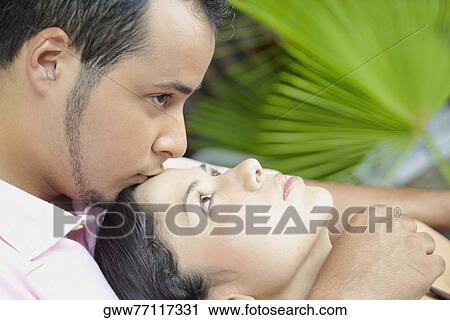 Stock Image - Close-up of a young man kissing a young woman on her forehead. Fotosearch