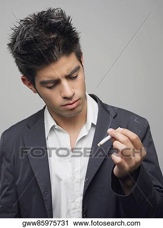 Close-up of a young man looking at a burning cigarette View Large Photo Image Stock Image - Close-up of a young man looking at a burning cigarette. Fotosearch