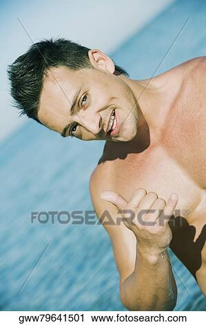 Close-up of a young man making thumbs up sign View Large Photo Image Stock Image - Close-up of a young man making thumbs up sign. Fotosearch
