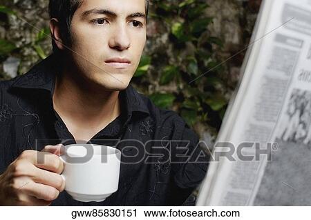 Stock Image - Close-up of a young man reading a newspaper. Fotosearch