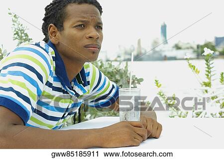 Close-up of a young man sitting at the table View Large Photo Image Stock Image - Close-up of a young man sitting at the table. Fotosearch
