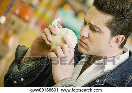 Close-up of a young man smelling a fruit View Large Photo Image Stock Image - Close-up of a young man smelling a fruit. Fotosearch