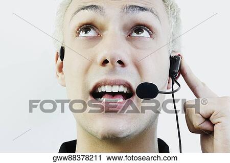 Close-up of a young man wearing headset and talking View Large Photo Image Stock Image - Close-up of a young man wearing headset and talking. Fotosearch