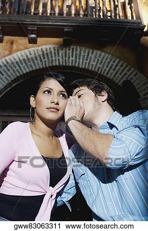Close-up of a young man whispering into a young woman's ear View Large Photo Image Stock Image - Close-up of a young man whispering into a young woman's ear. Fotosearch
