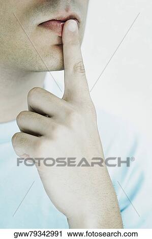 Close-up of a young man with his finger on his lips View Large Photo Image Stock Image - Close-up of a young man with his finger on his lips. Fotosearch