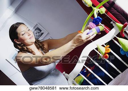 Close-up of a young pregnant woman adjusting toys in a crib View Large Photo Image Stock Image - Close-up of a young pregnant woman adjusting toys in a crib. Fotosearch