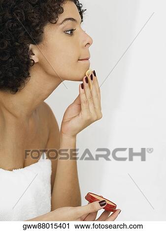 Close-up of a young woman applying face powder on her face View Large Photo Image Stock Image - Close-up of a young woman applying face powder on her face. Fotosearch