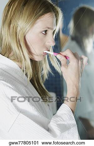 Stock Image - Close-up of a young woman brushing her teeth. Fotosearch