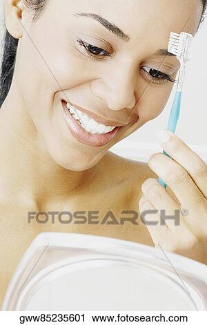 Stock Image - Close-up of a young woman combing her eyebrow. Fotosearch