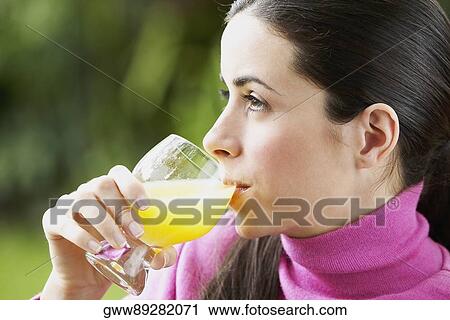 Stock Image - Close-up of a young woman drinking a glass of juice. Fotosearch