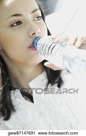 Close-up of a young woman drinking water from a bottle View Large Photo Image Stock Image - Close-up of a young woman drinking water from a bottle. Fotosearch
