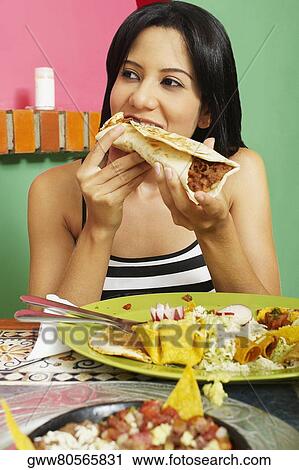 Stock Image - Close-up of a young woman eating a wrap sandwich. Fotosearch